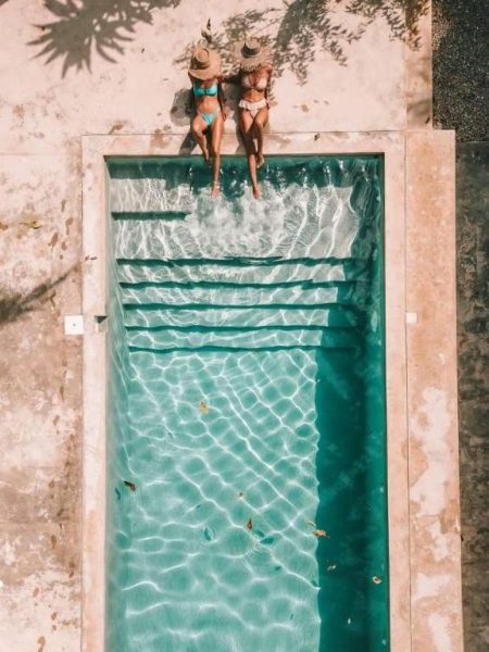 Vista aérea de la piscina exterior de Residencia El Balatà con dos turistas sentadas en el borde