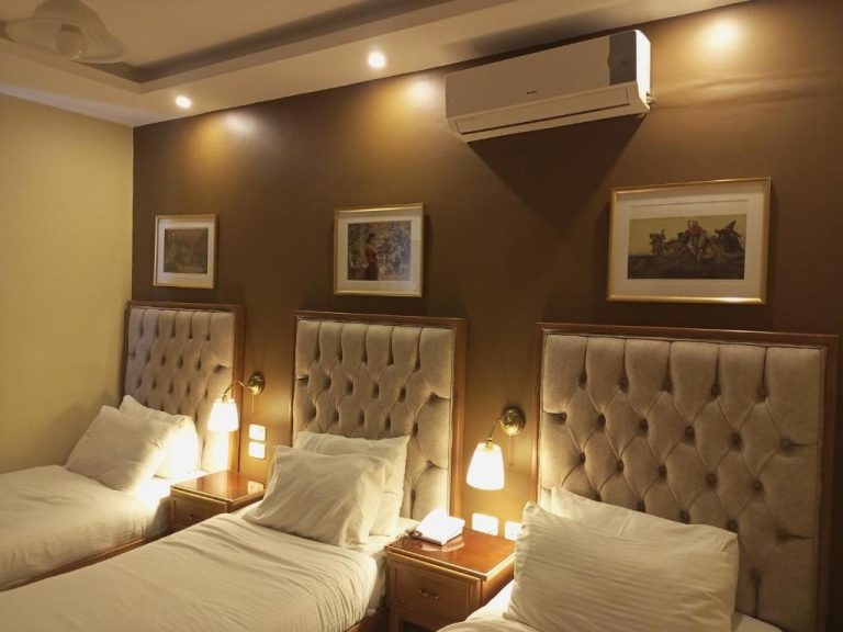 Habitación triple con tres camas individuales y cabeceros capitoné en el Mariam Hotel