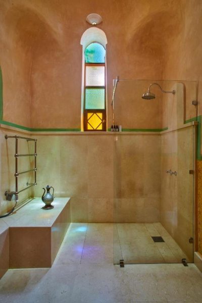 Lujoso baño estilo hammam con ducha de lluvia y ventana árabe en Al Moudira Hotel