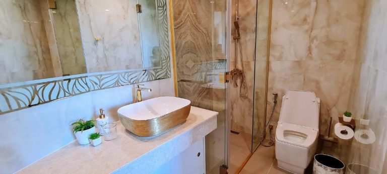 Baño de lujo con mármol, ducha de cristal y lavabo dorado en Copacabana Jomtien Condo Pattaya