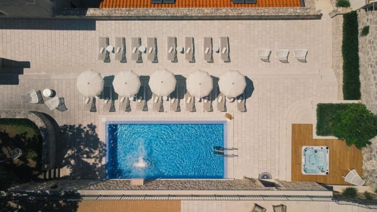 Vista aérea de la piscina exterior con tumbonas y sombrillas del Palace Natali