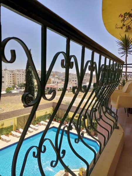 Vista desde el balcón con barandilla de hierro forjado hacia la piscina exterior del Mariam Hotel
