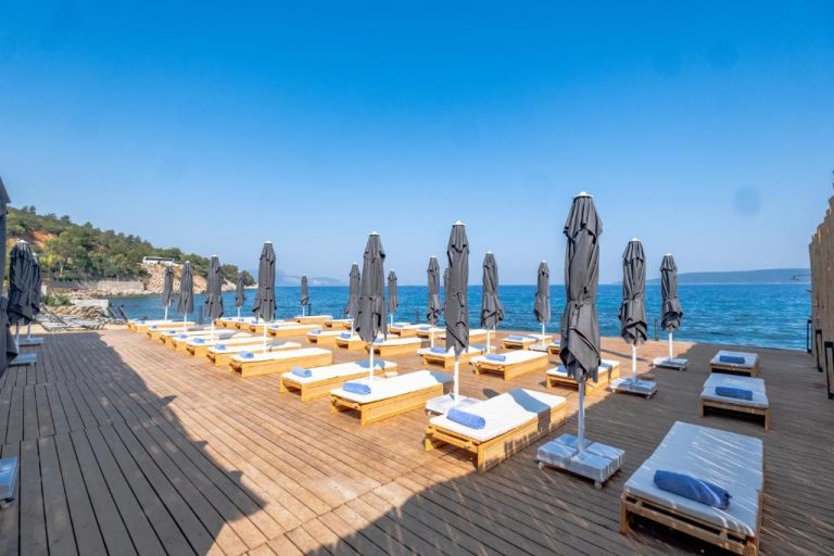 Terraza de madera con tumbonas y sombrillas frente al mar en el hotel İsolina Bodrum