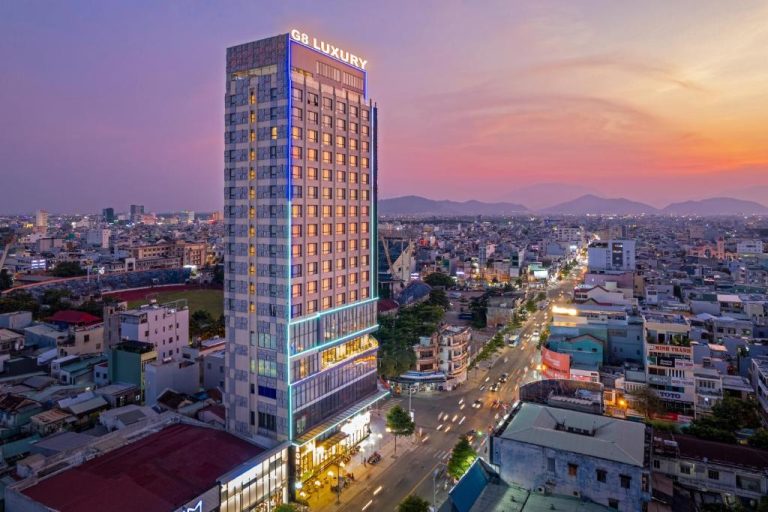 Vista aérea nocturna del G8 Luxury Hotel Da Nang con skyline de la ciudad al atardecer