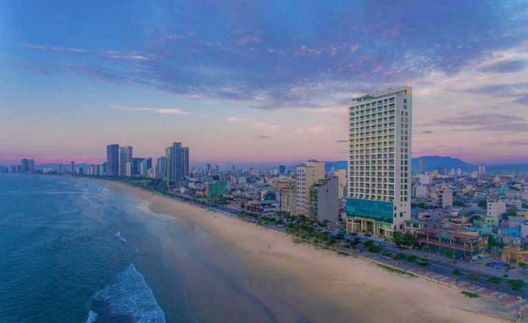 Vista aérea del Le Sands Oceanfront Danang Hotel frente a la playa de arena y el skyline de Da Nang