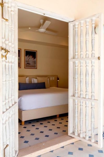 Habitación doble con puerta colonial blanca y suelo de mosaico en B Haus Hotel Boutique