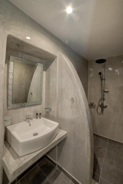 Baño moderno con ducha de lluvia y lavabo empotrado en piedra en Remvi Suites