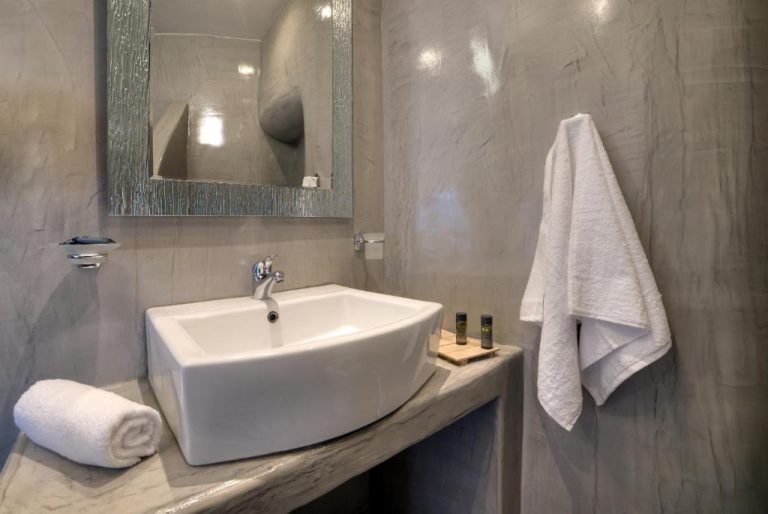 Baño moderno con lavabo de diseño sobre encimera de mármol en Remvi Suites
