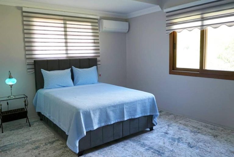 Habitación doble con cama azul, aire acondicionado y ventana en Doga Ciftlik Konaklama
