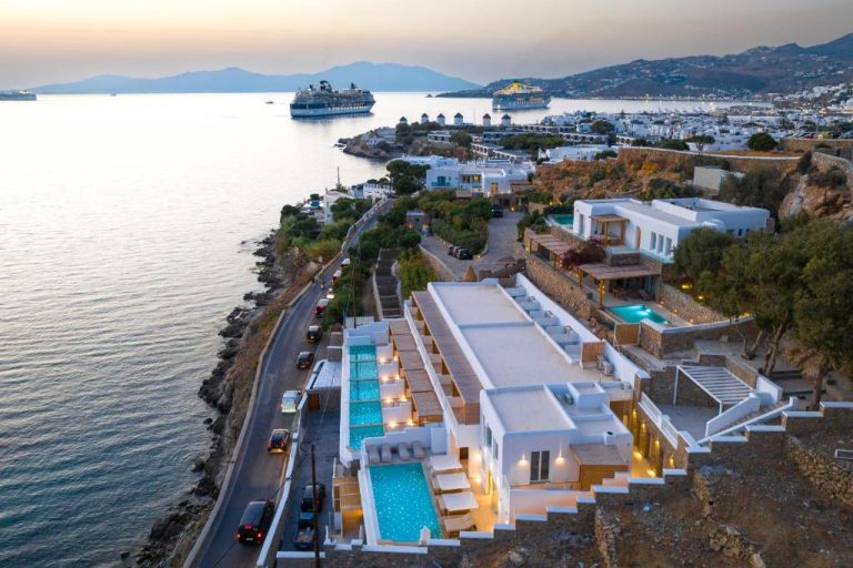 Vista aérea del Icon Mykonos con piscinas infinitas frente al mar y cruceros al atardecer