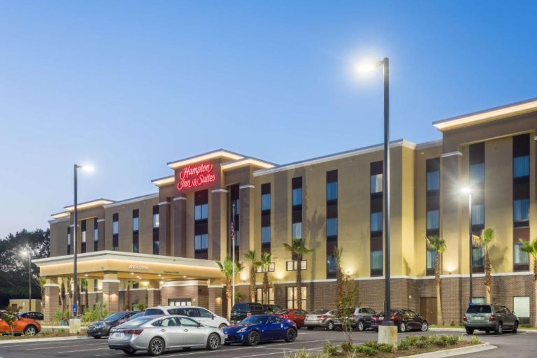Fachada exterior iluminada del Hampton Inn & Suites Fort Walton Beach con aparcamiento y palmeras