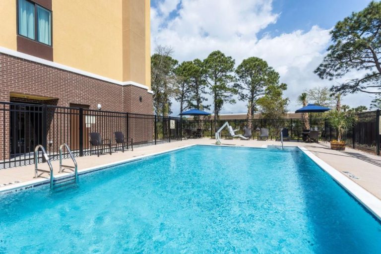 Piscina exterior con tumbonas y sombrillas azules del Hampton Inn & Suites Mary Esther Fort Walton Beach