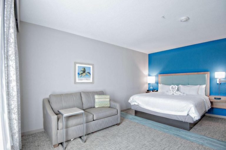 Habitación king con pared azul y sofá en Hampton Inn & Suites Mary Esther Fort Walton Beach