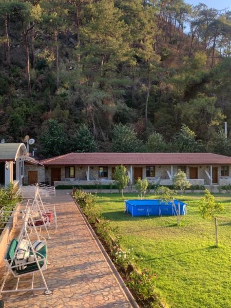 Piscina exterior y jardín verde del Doga Ciftlik Konaklama rodeado de montañas y naturaleza