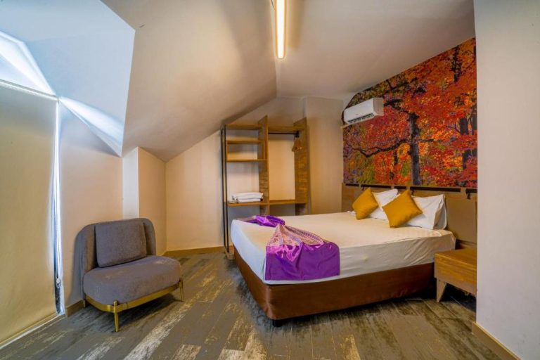 Habitación doble con cama matrimonial y cuadro otoñal en Lupo Libero Hotel Spa