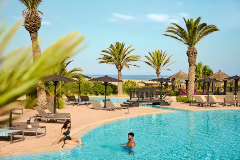 Piscina exterior con tumbonas y palmeras del hotel Robinson Agadir All Inclusive con vistas al mar