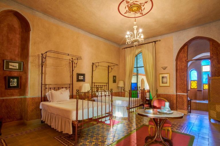 Habitación doble con camas de hierro forjado y decoración árabe clásica en Al Moudira Hotel