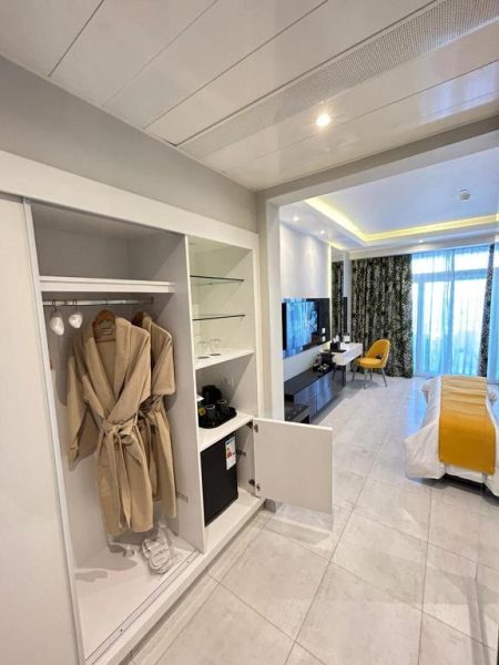 Habitación con armario abierto, albornoz y minibar en Naama Bay Suites & SPA