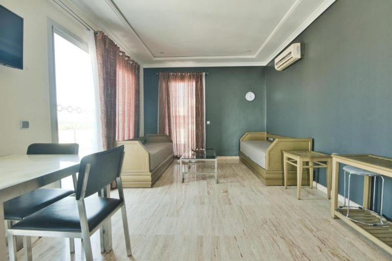 Salón amplio con sofás, mesa de comedor y aire acondicionado en Appart Hôtel Founty Beach