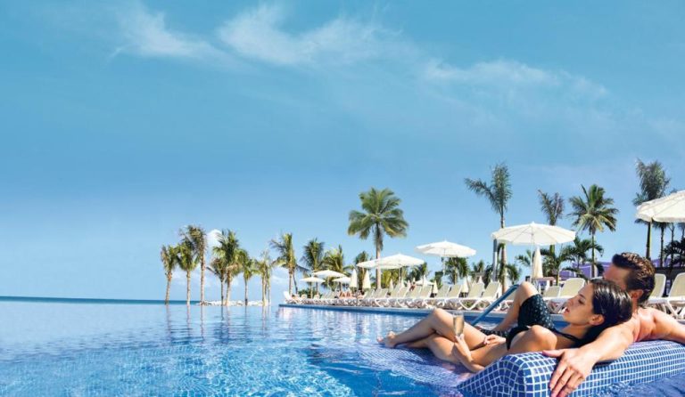 Pareja relajándose en la piscina infinita con vistas al mar del Riu Palace Jamaica Adults Only All Inclusive