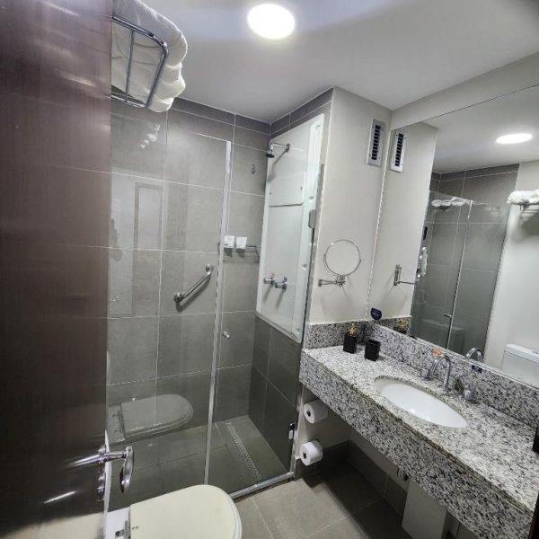 Baño moderno con ducha de cristal y encimera de granito en el hotel Suíte Premiere