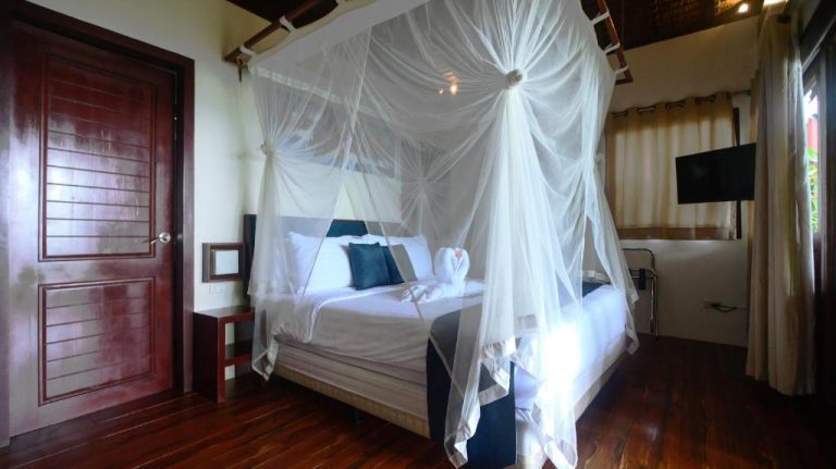 Habitación con cama dosel y mosquitera en Last Frontier Beach Resort Adults Only, Filipinas