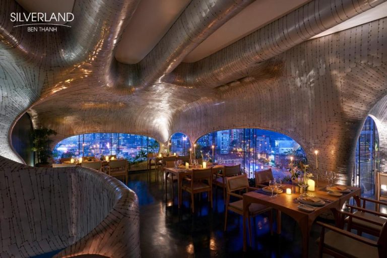 Restaurante de diseño futurista con techo ondulado y vistas nocturnas de la ciudad en Silverland Bến Thành