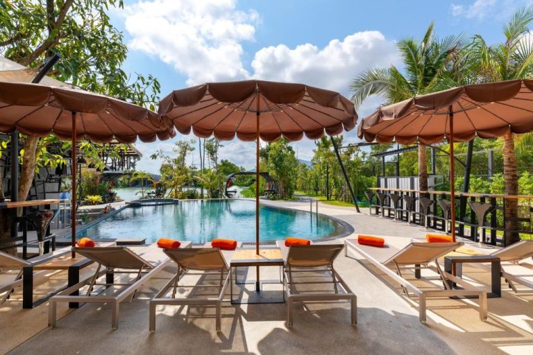 Piscina exterior con tumbonas y sombrillas del Samui Fishing Club and Resort rodeada de palmeras