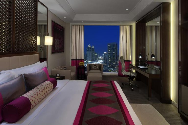Habitación deluxe con cama king y vistas nocturnas al skyline de Dubái en el Taj Dubai