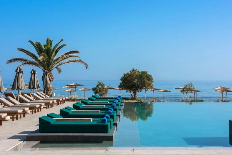 Piscina infinita con tumbonas verdes y vistas al mar del Hotel Paralos Kosta Alímia
