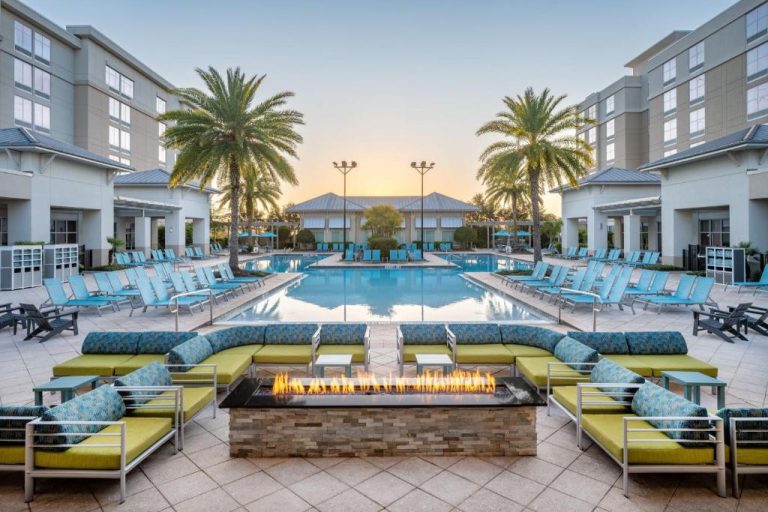 Piscina exterior con chimenea y tumbonas azules del SpringHill Suites Orlando Flamingo Crossings al atardecer