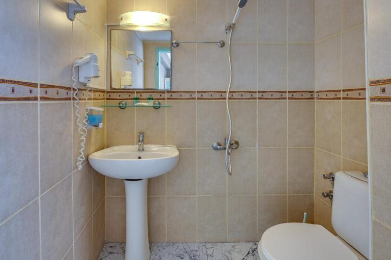 Baño completo con ducha, lavabo y aseo del Hikmethan Otel con acabados en azulejos beige