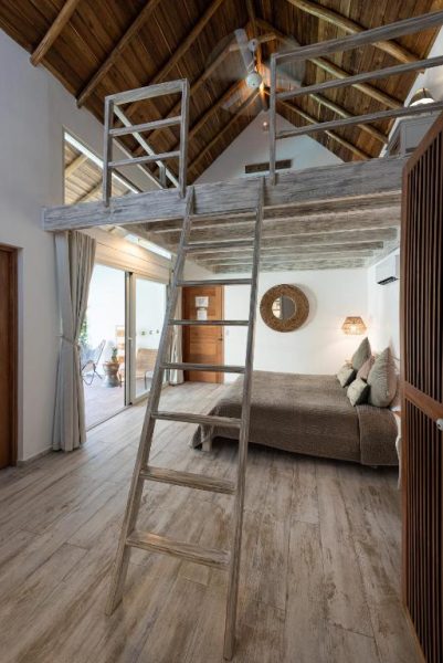 Habitación con altillo y escalera de madera rústica en Takuma Boutik Hotel con techo de madera