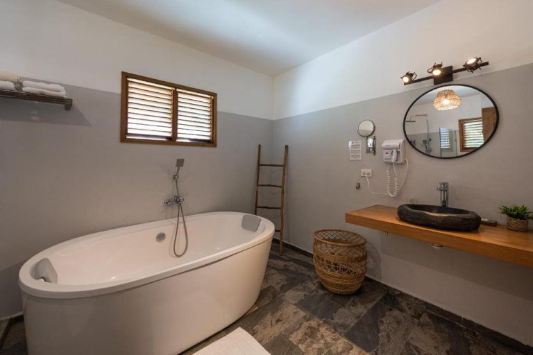 Baño de lujo con bañera exenta blanca y lavabo de piedra natural en Takuma Boutik Hotel