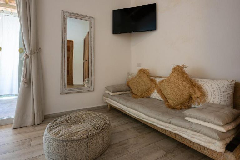 Salón bohemio con sofá cama y cojines de yute en Takuma Boutik Hotel, decoración natural y TV