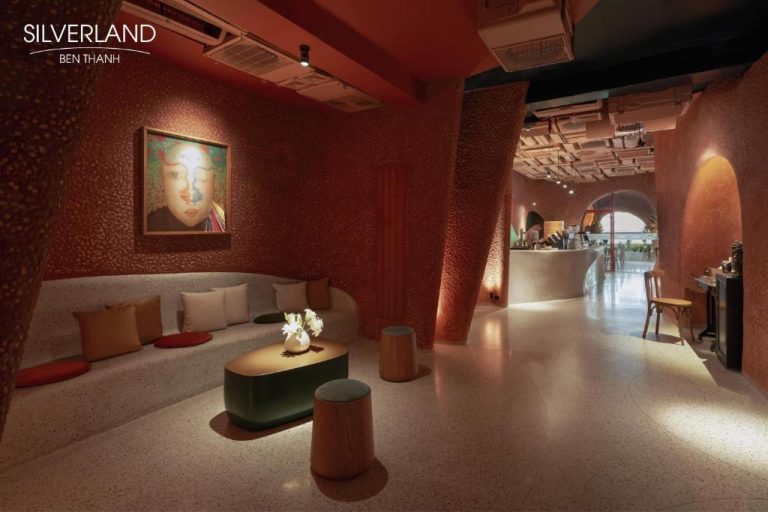 Lobby lounge con sofá y decoración artística en tonos rojos del hotel Silverland Bến Thành en Vietnam