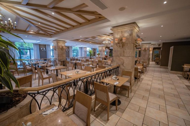 Elegante restaurante interior del Maritim Antonine Hotel & Spa con mesas de madera y columnas de mármol