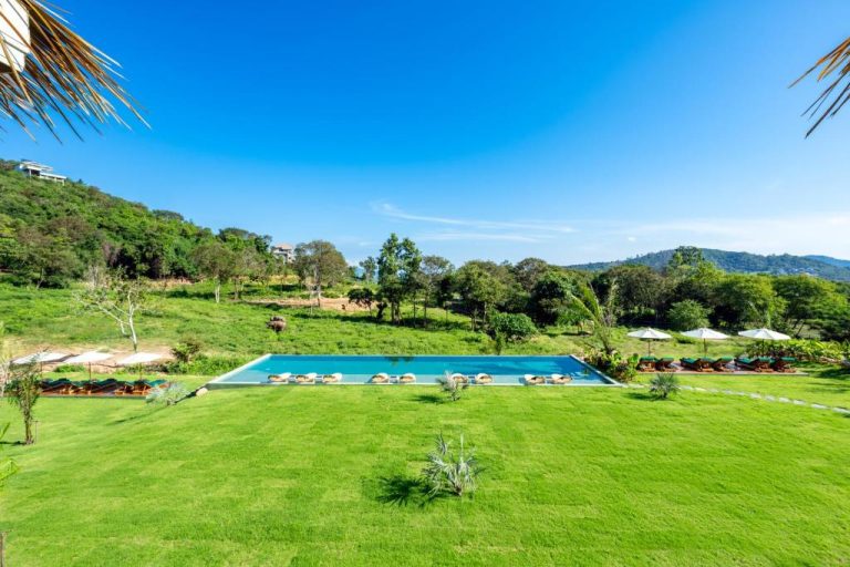 Piscina infinita rodeada de jardines tropicales y montañas en Wild Cottages Elephant Sanctuary Resort