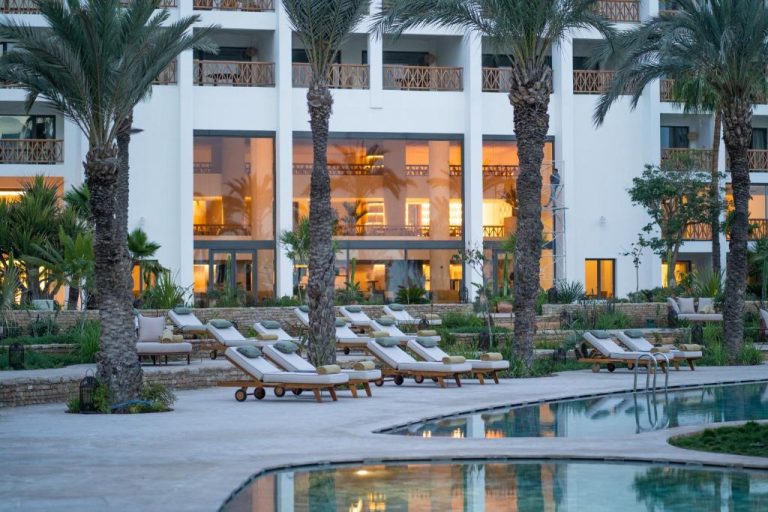 Piscina exterior con tumbonas y palmeras del hotel The View Agadir al atardecer
