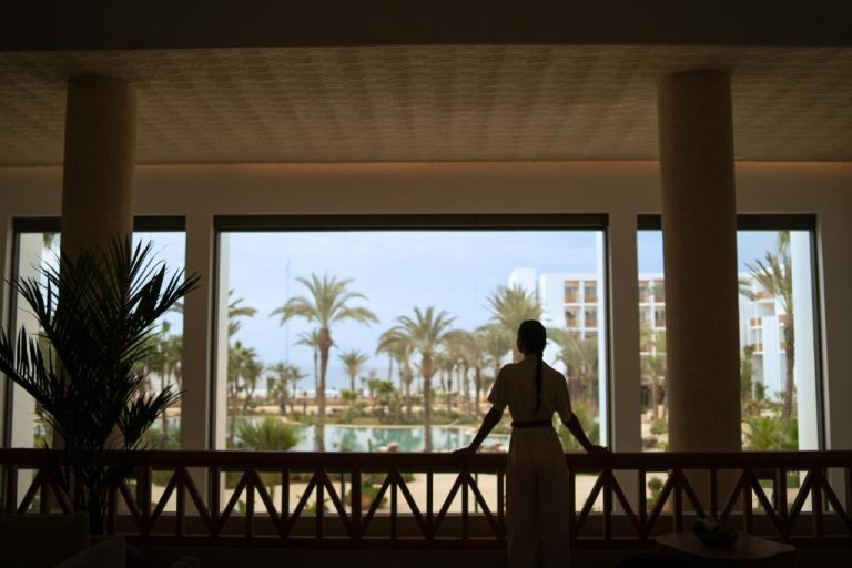 Mujer contemplando las vistas al jardín con palmeras desde el lobby del The View Agadir