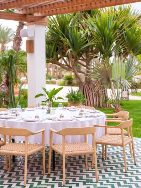 Terraza de restaurante exterior con mesa redonda y jardines tropicales en The View Agadir