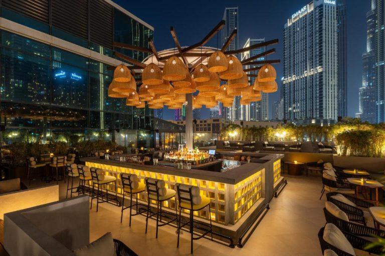 Terraza bar en la azotea del Taj Dubai con vistas al skyline nocturno y barra iluminada
