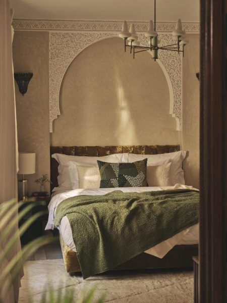 Habitación doble con arco morisco decorado y ropa de cama verde en IZZA Marrakech