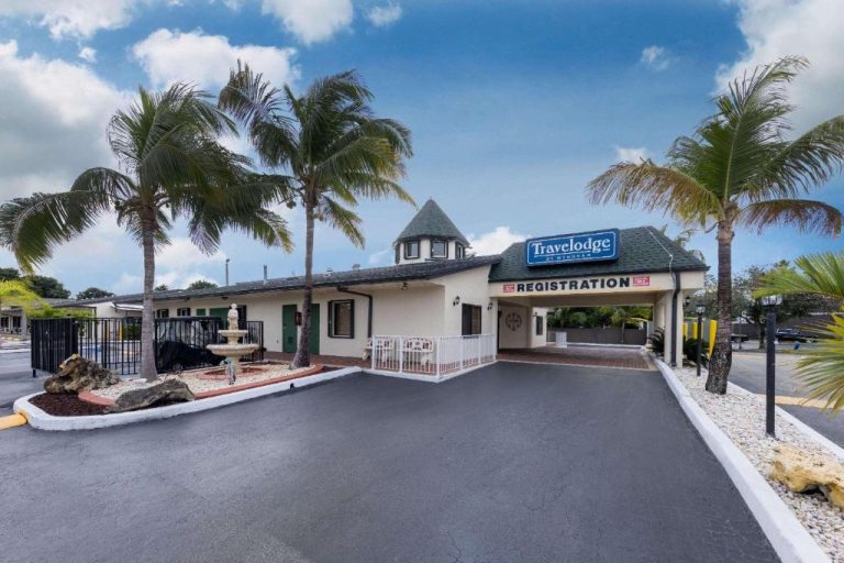 Fachada y entrada principal del Travelodge by Wyndham Florida City con palmeras y recepción