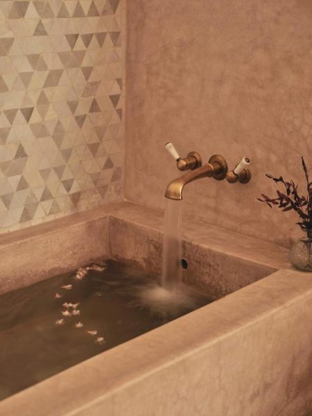 Bañera de piedra con grifo dorado vintage y flores en el spa del hotel IZZA Marrakech