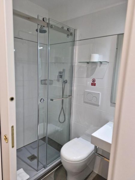 Baño moderno con ducha de cristal, inodoro y lavabo del Boutique Hôtel Neptune Nice