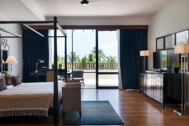 Suite de lujo con cama de dosel y terraza con vistas a palmeras en The Blue Water Bawa Heritage Resort