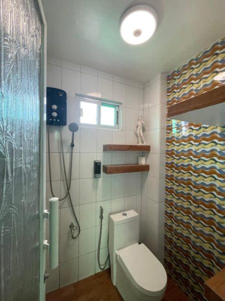 Baño completo con ducha eléctrica y azulejos decorativos del Italy Condotel Darasa en Filipinas
