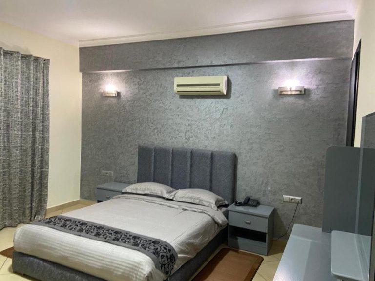 Habitación doble de lujo con cama king size y pared gris texturizada en Appart Hôtel Founty Beach