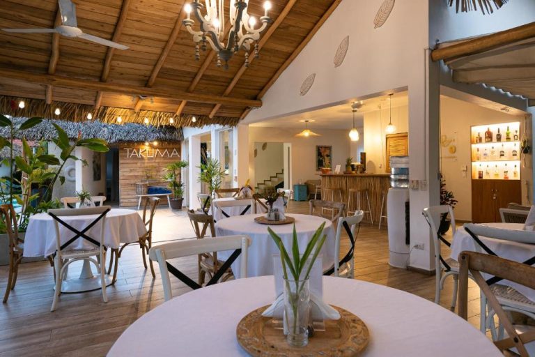 Restaurante interior con mesas blancas y decoración tropical del Takuma Boutik Hotel